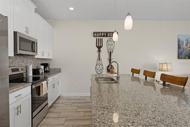 kitchen featuring decorative backsplash, white cabinetry, light stone countertops, sink, and stainless steel appliances