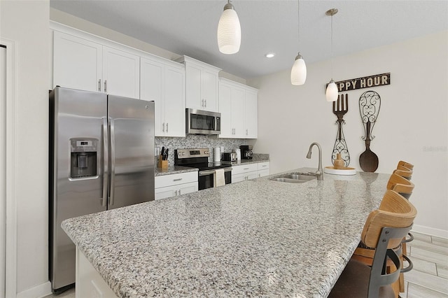 kitchen featuring sink, appliances with stainless steel finishes, a kitchen island with sink, tasteful backsplash, and white cabinets