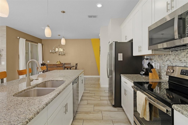 kitchen featuring tasteful backsplash, white cabinetry, appliances with stainless steel finishes, and light stone countertops