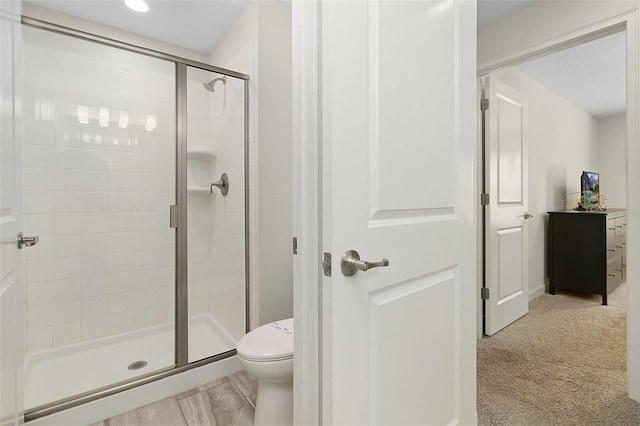 bathroom featuring wood-type flooring, toilet, and a shower with shower door