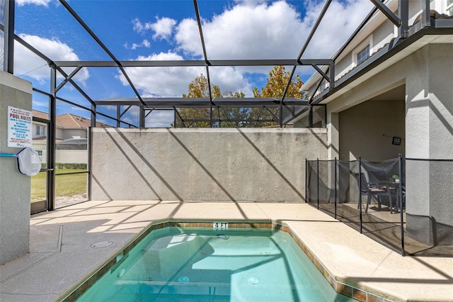 view of pool with glass enclosure and a patio