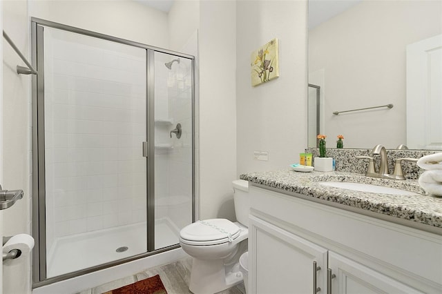 bathroom featuring an enclosed shower, vanity, and toilet