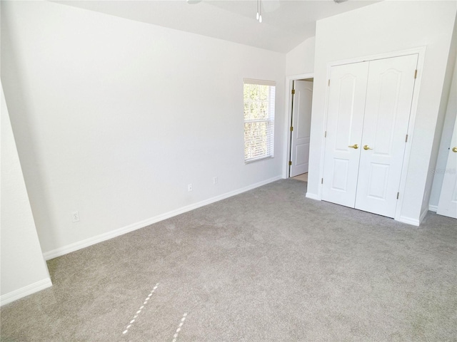 unfurnished bedroom featuring light carpet, vaulted ceiling, and a closet