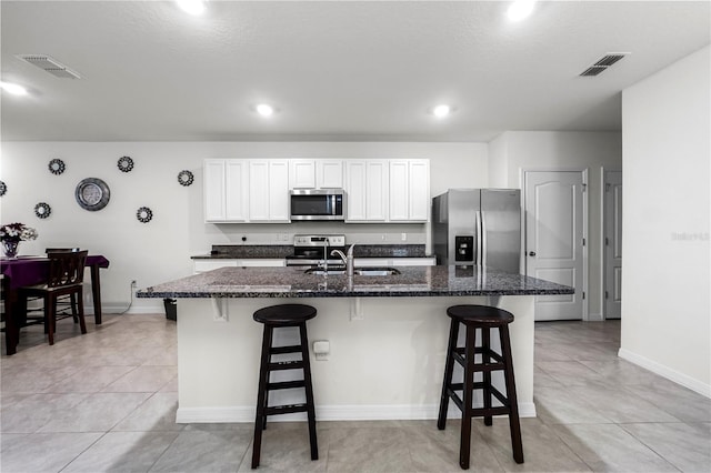 kitchen with appliances with stainless steel finishes, sink, a center island with sink, and white cabinets