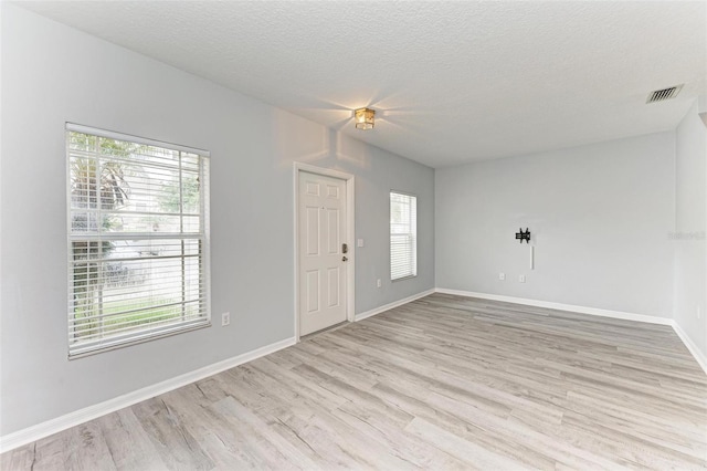 unfurnished room featuring a textured ceiling, light hardwood / wood-style floors, and a wealth of natural light