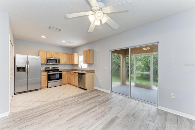 kitchen with appliances with stainless steel finishes, light wood-type flooring, light brown cabinetry, ceiling fan, and sink