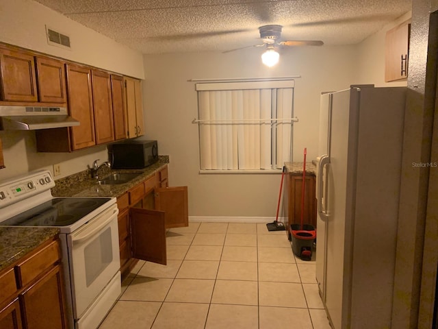 kitchen with ceiling fan, white appliances, sink, light tile floors, and wall chimney exhaust hood