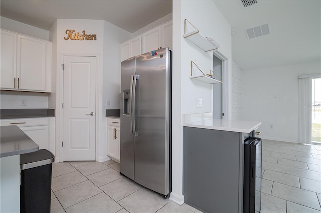 kitchen with kitchen peninsula, stainless steel fridge, white cabinets, and light tile floors