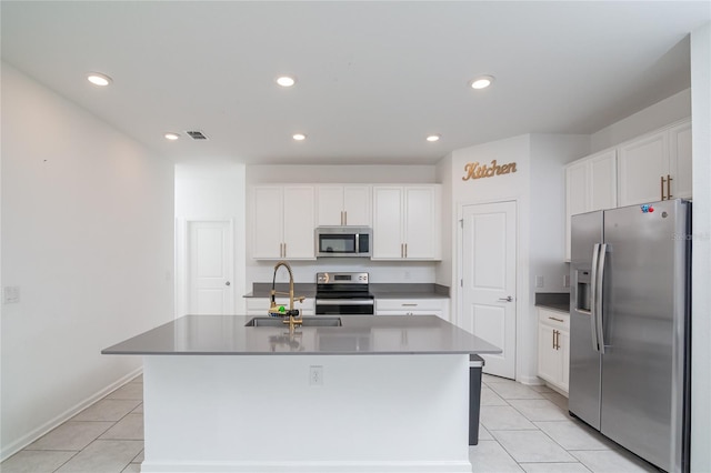 kitchen featuring light tile floors, a kitchen island with sink, appliances with stainless steel finishes, and white cabinetry