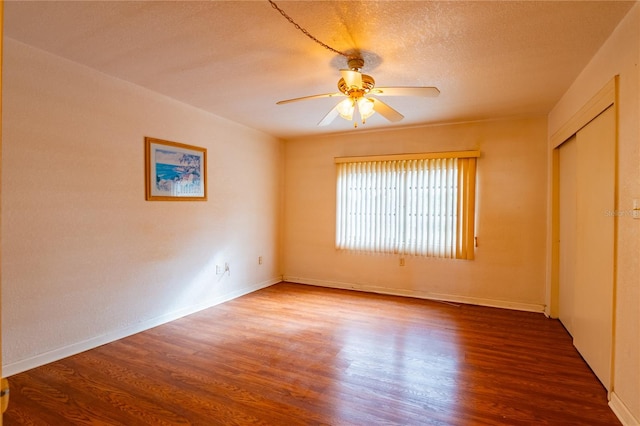 unfurnished room featuring a textured ceiling, ceiling fan, and dark wood-type flooring