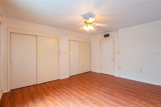 unfurnished bedroom featuring two closets, ceiling fan, and light wood-type flooring