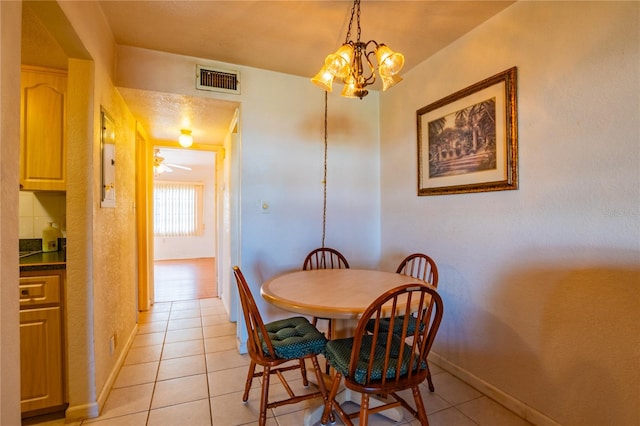 tiled dining area with ceiling fan with notable chandelier