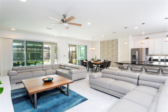 tiled living room with ceiling fan and sink