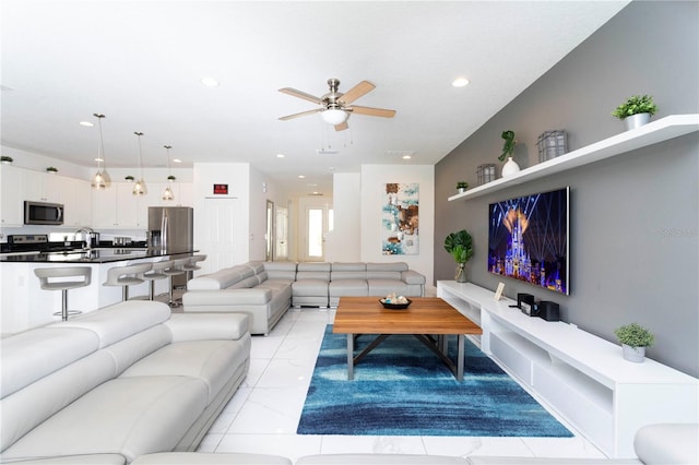 living room featuring ceiling fan, light tile floors, and sink