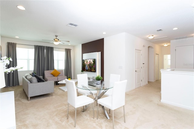 dining area with ceiling fan and light colored carpet