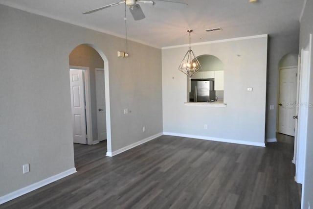 empty room featuring ornamental molding, ceiling fan with notable chandelier, and dark wood-type flooring