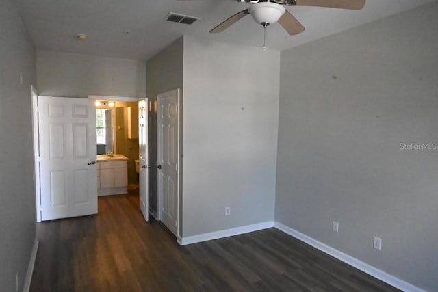 unfurnished bedroom featuring ceiling fan, connected bathroom, and dark wood-type flooring