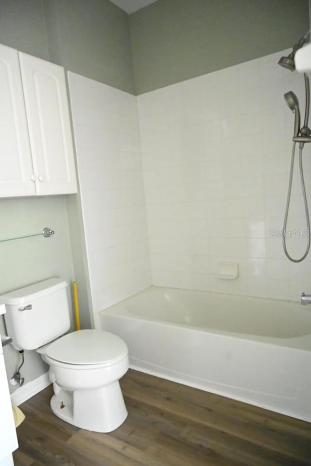 bathroom featuring tiled shower / bath, toilet, and hardwood / wood-style flooring