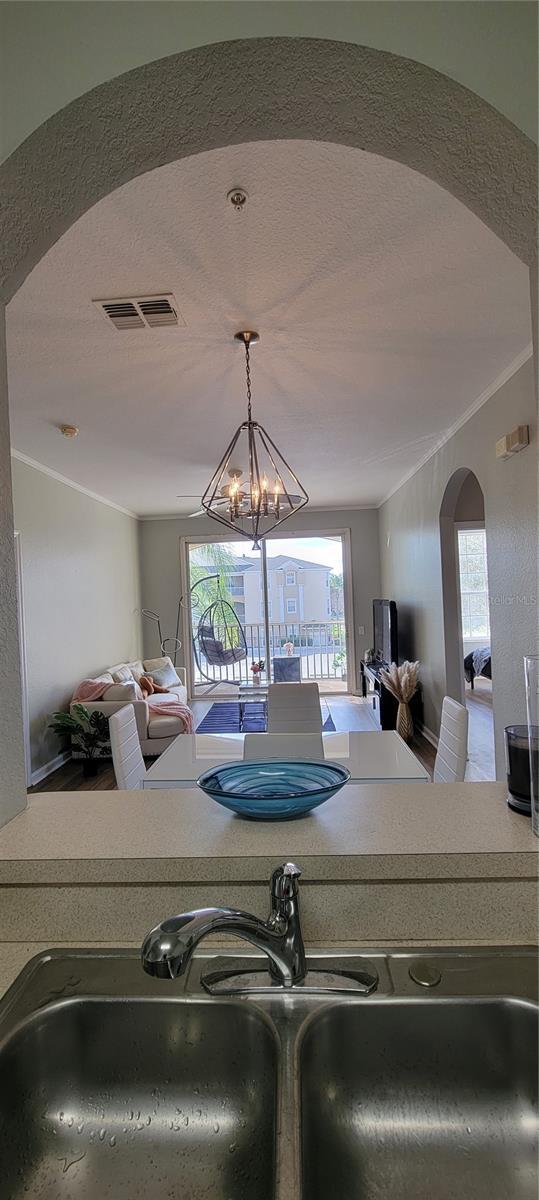 kitchen featuring decorative light fixtures, sink, crown molding, a textured ceiling, and an inviting chandelier