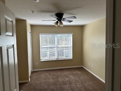 carpeted empty room with a textured ceiling and ceiling fan