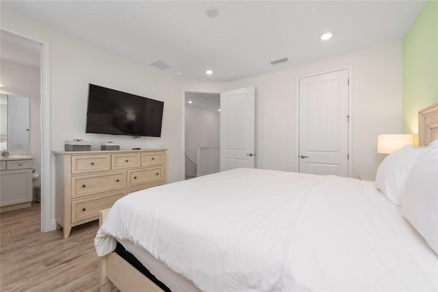 bedroom with light hardwood / wood-style floors and ensuite bathroom