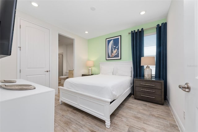 bedroom with ensuite bath and light hardwood / wood-style flooring