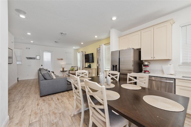 dining area with a textured ceiling and light wood-type flooring