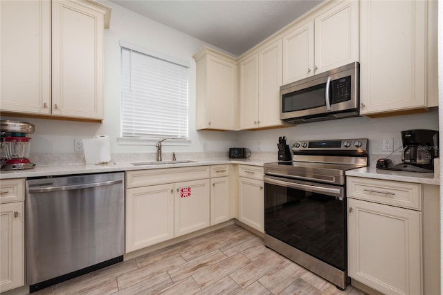 kitchen with cream cabinetry, light wood-type flooring, sink, and stainless steel appliances