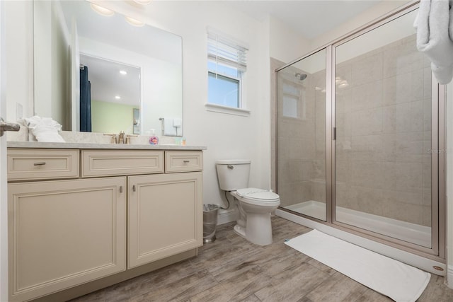 bathroom featuring wood-type flooring, toilet, walk in shower, and vanity