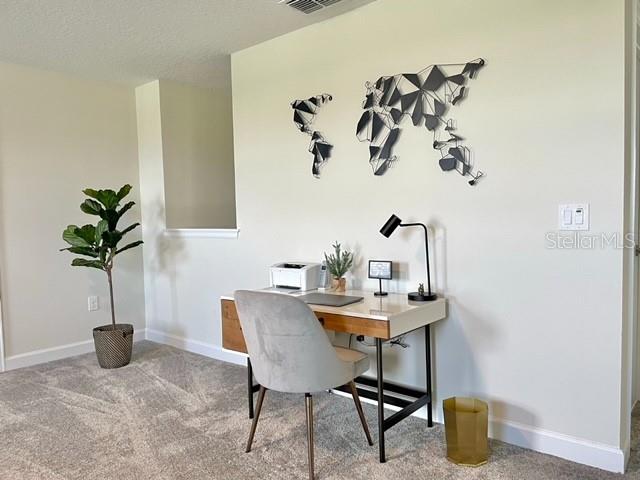 carpeted office with a textured ceiling