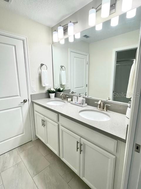 bathroom with dual sinks, tile floors, oversized vanity, and a textured ceiling