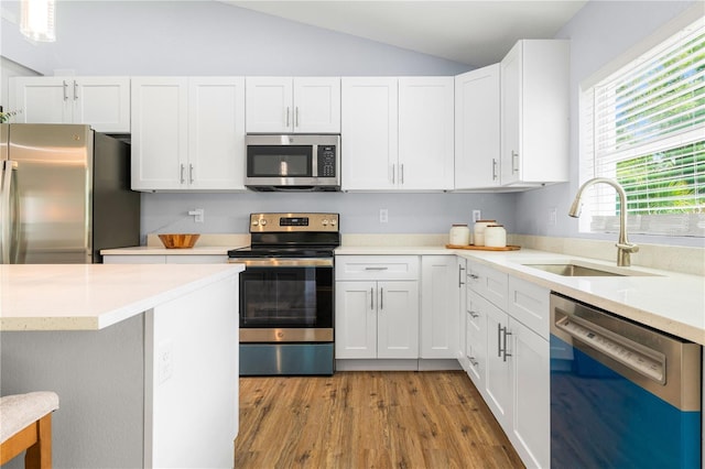 kitchen featuring white cabinetry, sink, appliances with stainless steel finishes, light hardwood / wood-style flooring, and lofted ceiling