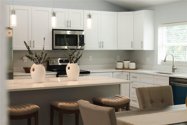 kitchen with white cabinetry, sink, a breakfast bar area, light stone counters, and appliances with stainless steel finishes