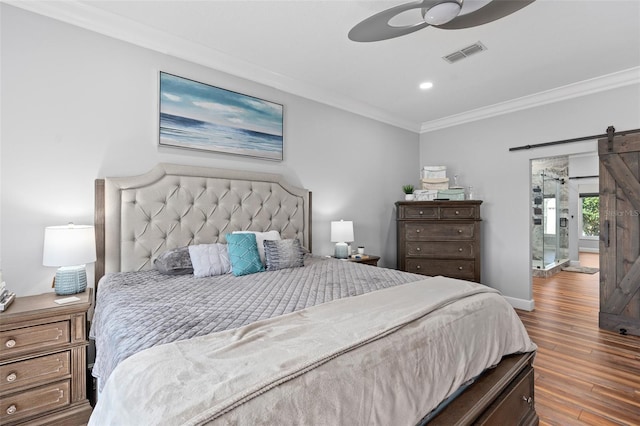 bedroom featuring crown molding, a barn door, hardwood / wood-style floors, and ceiling fan