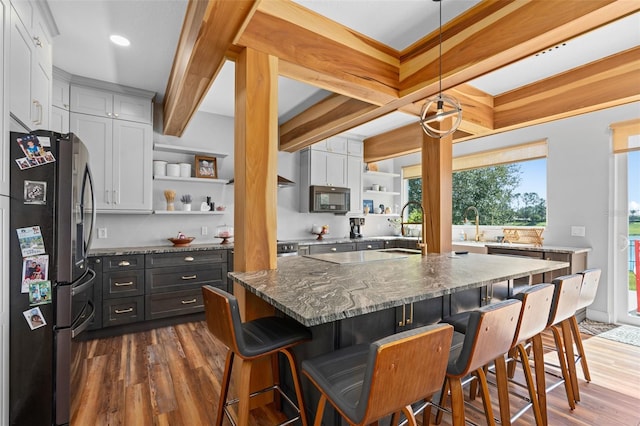 kitchen with a breakfast bar, decorative light fixtures, a center island, and stainless steel fridge with ice dispenser