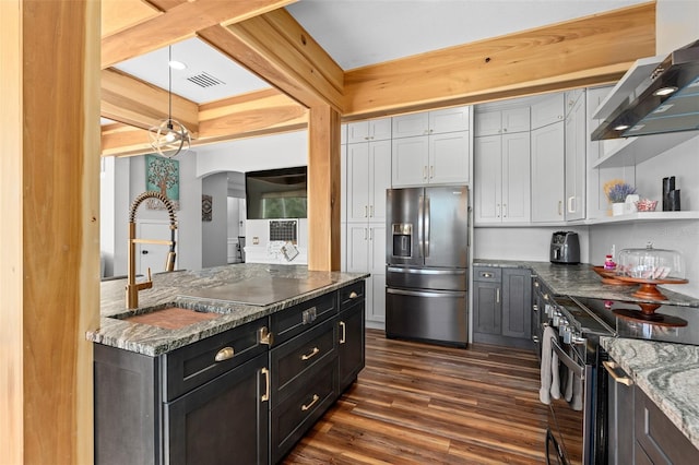 kitchen with dark hardwood / wood-style floors, sink, hanging light fixtures, stainless steel appliances, and wall chimney range hood