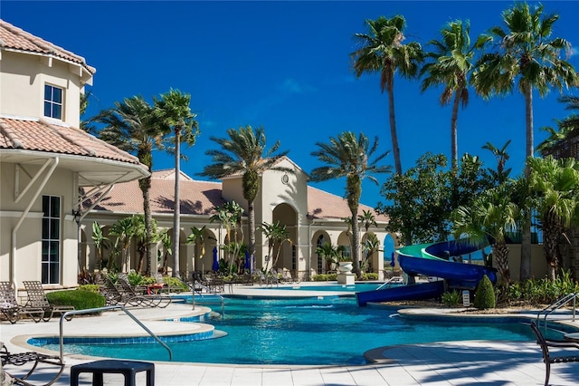 view of swimming pool with a water slide and a patio