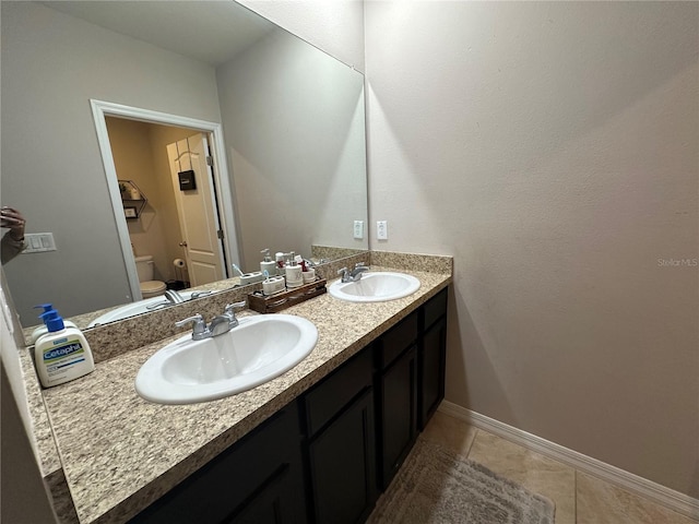 bathroom featuring tile floors, toilet, and dual vanity