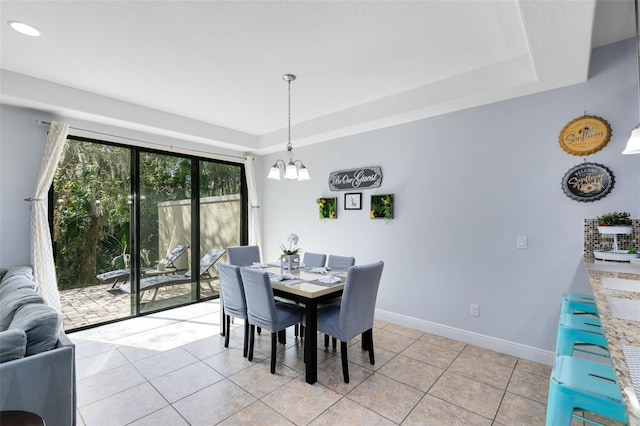 dining room with a chandelier, light tile patterned floors, and a raised ceiling