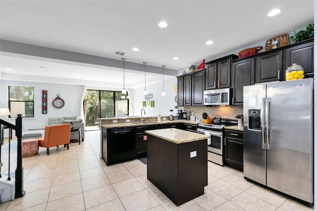 kitchen featuring kitchen peninsula, appliances with stainless steel finishes, tasteful backsplash, sink, and pendant lighting