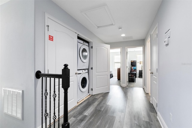 laundry room with hardwood / wood-style flooring and stacked washer and clothes dryer