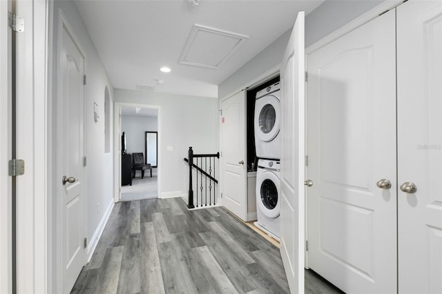 clothes washing area with light hardwood / wood-style flooring and stacked washer and clothes dryer