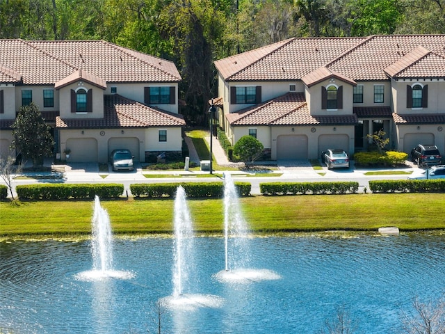 exterior space featuring a water view, a garage, and a lawn