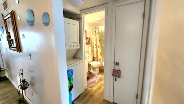 hall with stacked washer / drying machine and light hardwood / wood-style floors