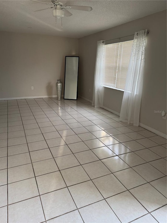 tiled spare room with a textured ceiling and ceiling fan