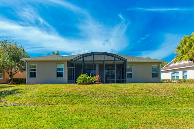 back of property with glass enclosure and a yard