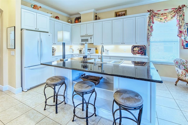 kitchen with a breakfast bar area, sink, white appliances, and light tile floors