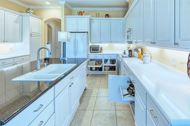 kitchen featuring white cabinetry, dark stone countertops, white appliances, sink, and light tile flooring