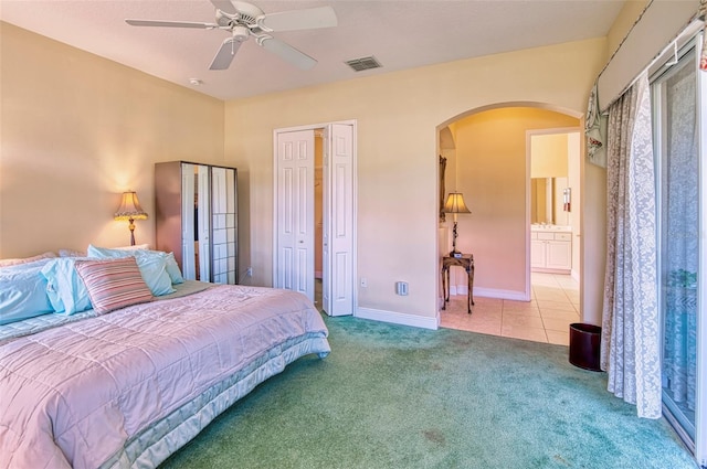 carpeted bedroom featuring ensuite bath and ceiling fan