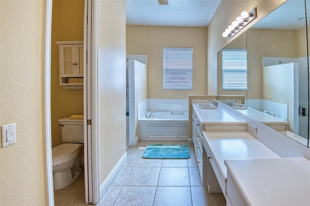 bathroom with a tub, tile flooring, a textured ceiling, toilet, and large vanity